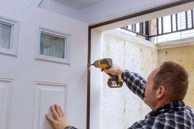 Hinges being screwed into a door replacement.