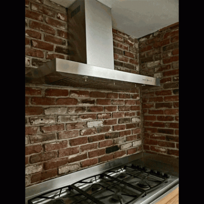 Vent hood installation on a brick wall.